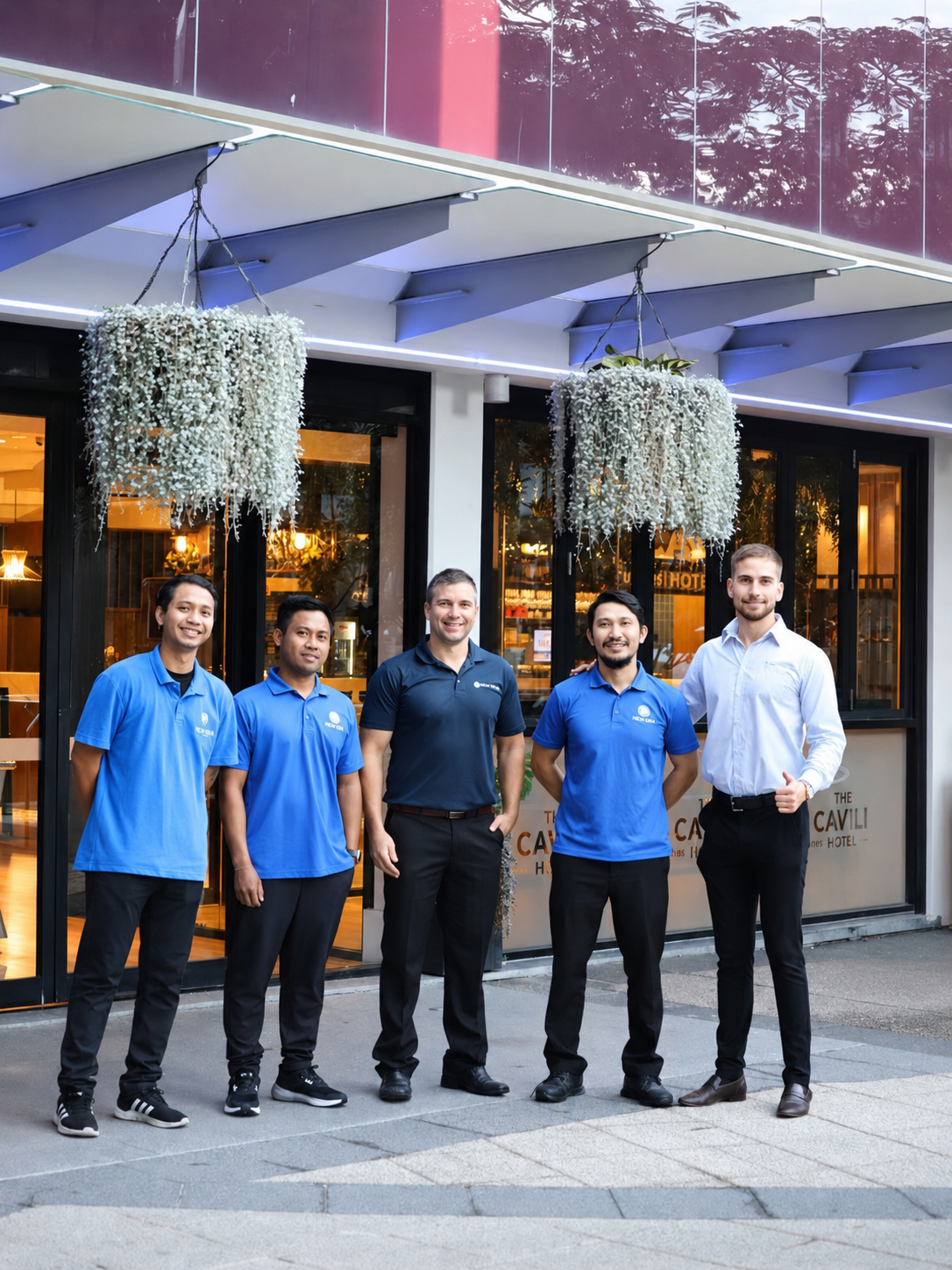 A New Era facility-services team standing together in branded uniforms outside a hotel they service